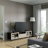 Soggiorno moderno con panca TV BESTÅ, tv a schermo piatto, tavolino in vetro, divano grigio e tende alla finestra.