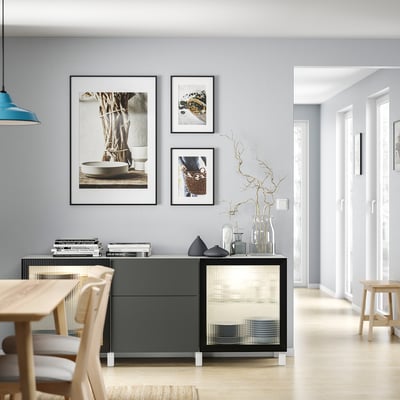 Soggiorno moderno con mobile contenitore BESTÅ grigio, tavolo e sedie in legno; porte in vetro, vasi e opere d'arte murali.