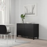 Camera moderna e minimalista: mobile BESTÅ nero, elegante e basso, in bianco e nero, accanto a scrivania e sedia bianche.