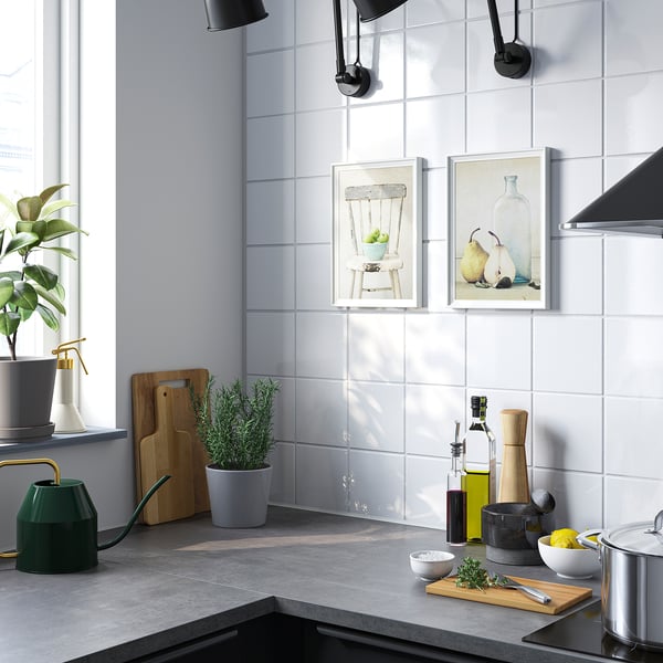 Cucina moderna con piastrelle bianche, poster di frutta e utensili da cucina.