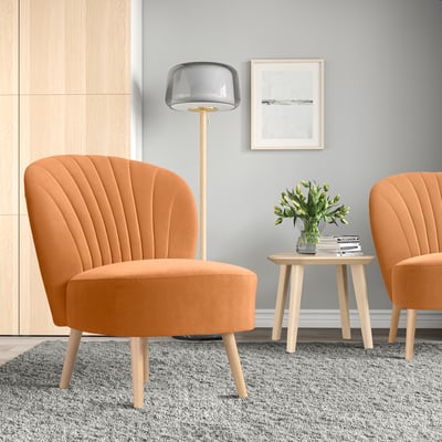 Camera moderna e minimalista con sedie BILLHAMN arancioni, tavolino in legno e lampada alta.