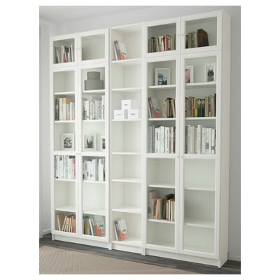Grande libreria BILLY bianca con ante in vetro e ripiani a giorno, che espone libri e decorazioni.