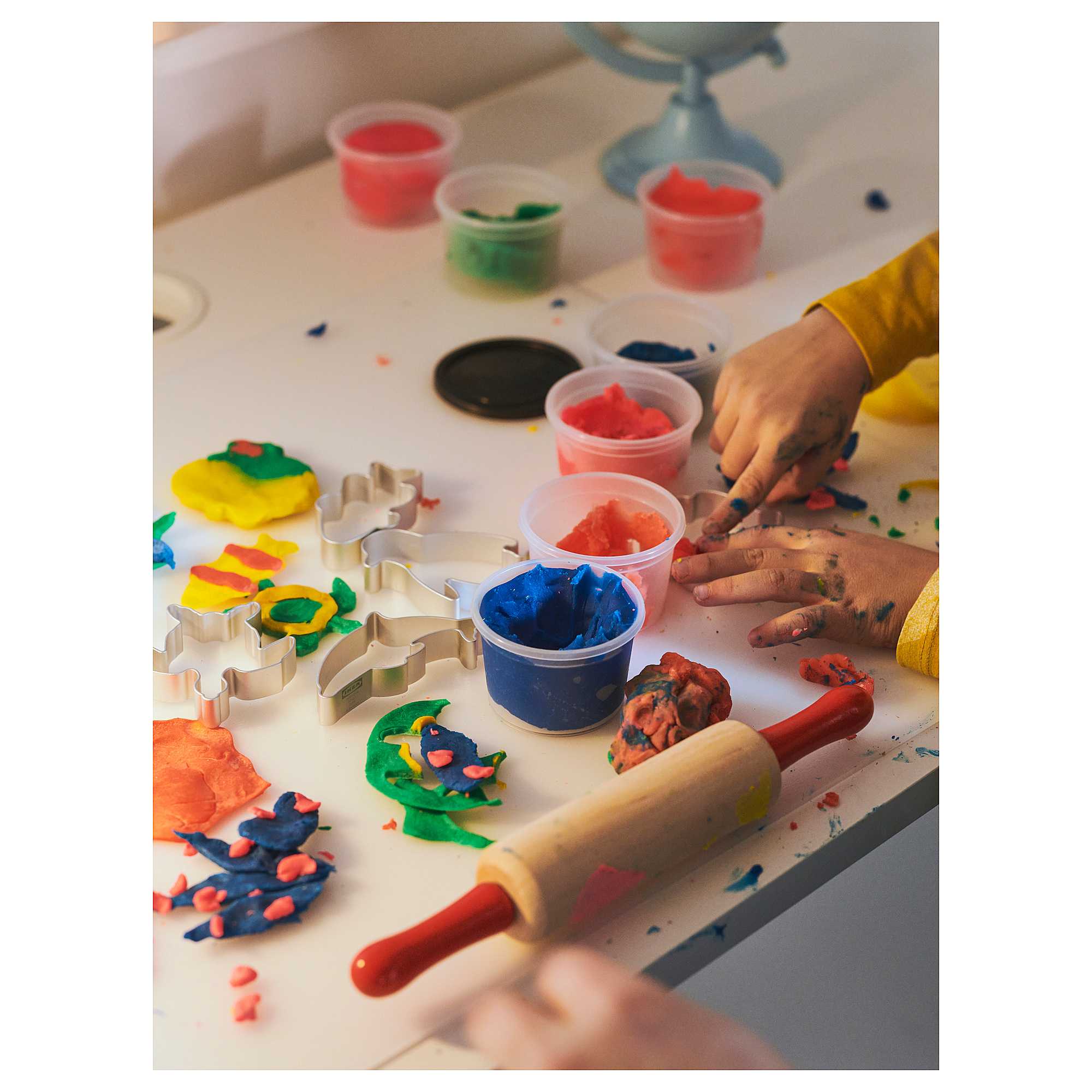 Bambini che giocano con impasti colorati e tagliapasta sagomati.