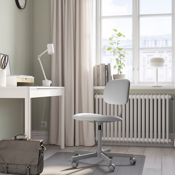 Configurazione minimalista dell'home office: scrivania bianca, sedia grigia, grande finestra, pianta e lampada.