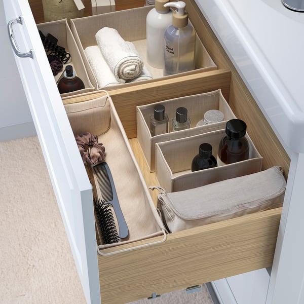 Cassetto organizzato con scatole morbide divise per articoli da toeletta, trucco e pennelli, utilizzando lo spazio in modo efficiente.