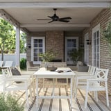 Set da pranzo all'aperto BONDHOLMEN: tavolo in acacia bianca e 8 sedie con cuscini sotto il portico.