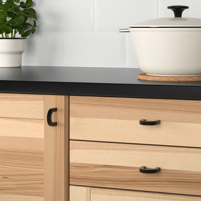 Cucina moderna con cassetti in legno chiaro e maniglie in metallo.