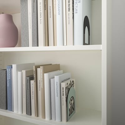 Libreria bianca con fermalibri colorati e oggetti decorativi.