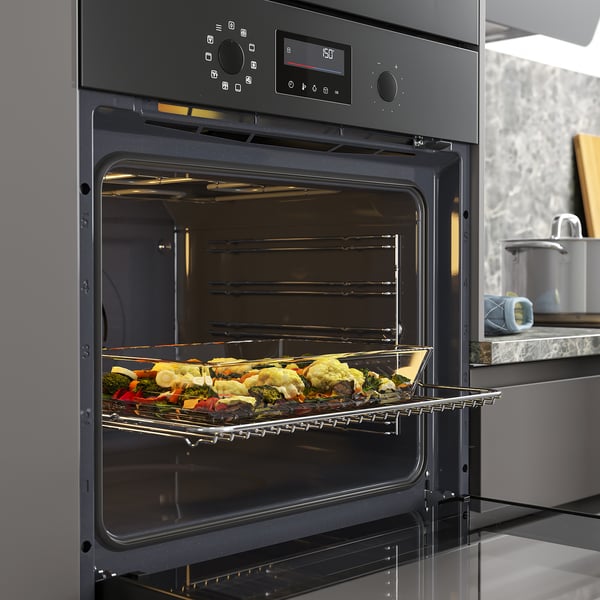 Forno nero che cuoce verdure colorate con distribuzione uniforme del calore.