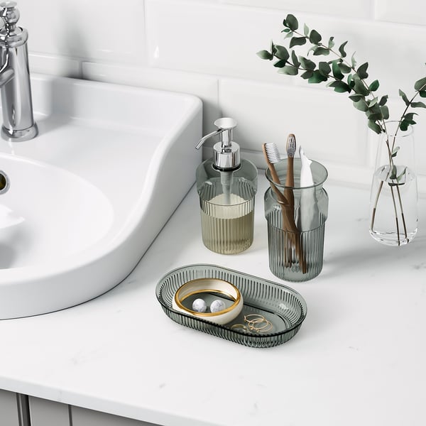 Lavandino da bagno con dispenser di sapone, portaspazzolino, vassoio e vaso. Accessori BROFJÄRDEN cromati sul piano di lavoro.