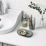 Lavandino da bagno con dispenser di sapone, portaspazzolino, vassoio e vaso. Accessori BROFJÄRDEN cromati sul piano di lavoro.