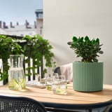 Tavolo da giardino con piante, calce, bicchieri, vista sulla città.