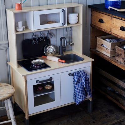 Cucina da gioco per bambini, bianca con dettagli neri, include lavello, fornelli, forno e accessori.