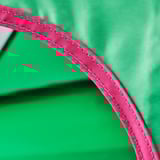 Primo piano di un robusto e vivace tessuto per tende con bordi rosa, che mostra cuciture di qualità e materiale resistente.