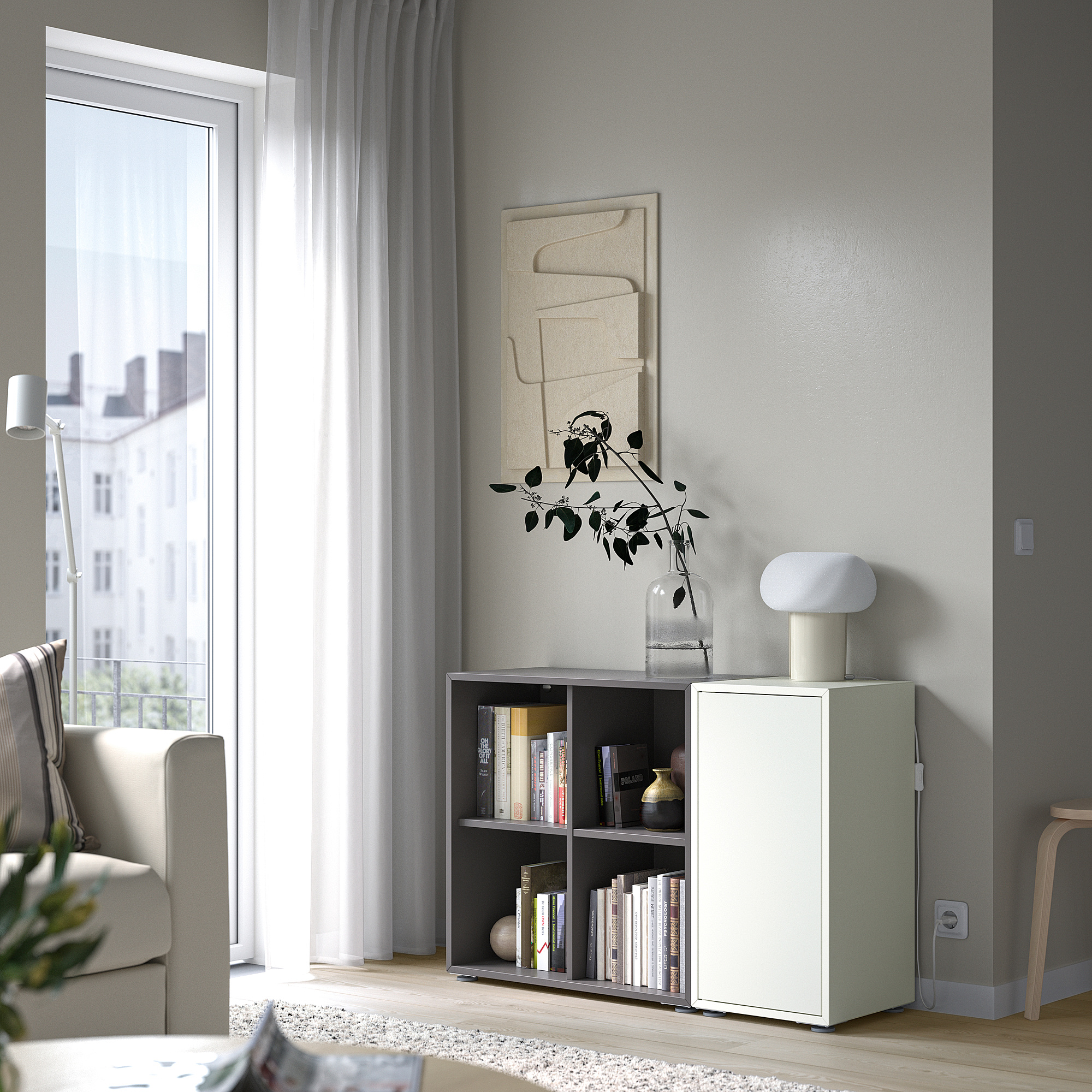 Soggiorno minimalista con contenitore EKET, libri, lampada, finestra, decorazioni.