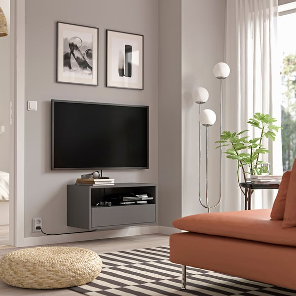 Soggiorno moderno con mobile tv a parete EKET grigio, schermo piatto e divano arancione.
