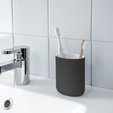 Bagno moderno con rubinetto cromato, portaspazzolino grigio e due spazzolini da denti su piano di lavoro bianco. EKOLN.