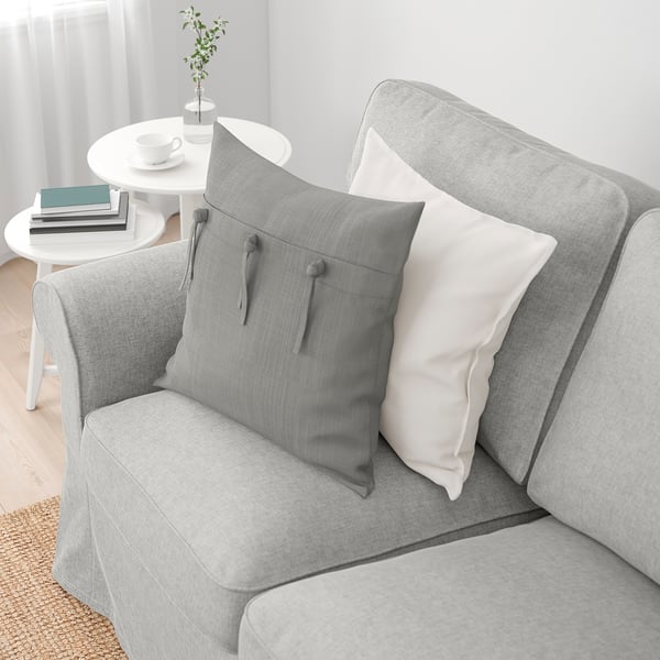 Divano grigio con cuscini EKTORP, tavolino bianco con libri.