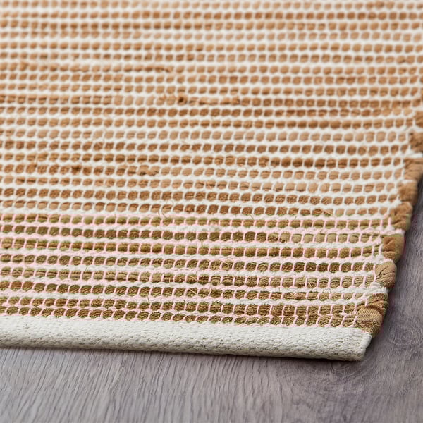 Primo piano di beige, tappeto di cotone tessuto a mano con intricati motivi a rombi, texture morbida.