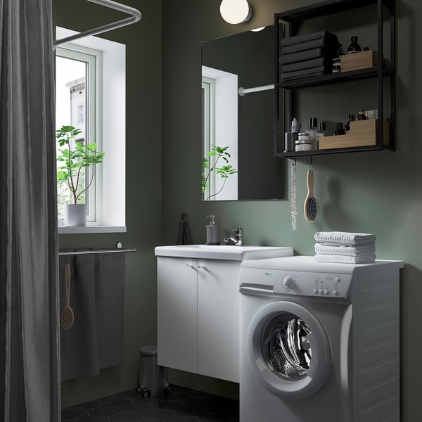Bagno moderno e verde con mobile ENHET, lavatrice, specchio, lavandino, piante e asciugamani.