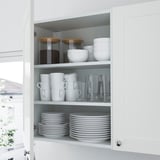 Mobile da cucina organizzato con piatti, tazze, ciotole e contenitori.