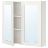 Un pensile ENHET bianco con due ante a specchio e due ripiani a giorno.