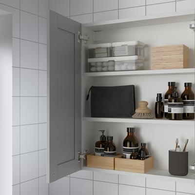 Mobile bagno con specchio, tre mensole e vari articoli da toeletta.