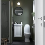 Un bagno compatto con mobile ENHET, lavabo, specchio rotondo, WC e porta doccia in vetro.