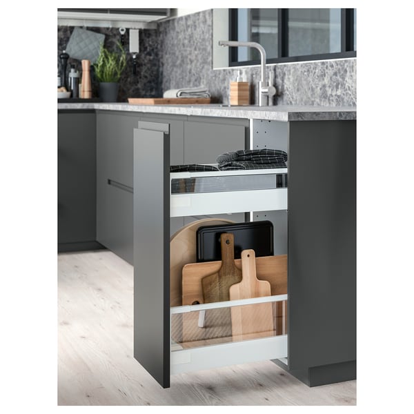 Cucina moderna con armadi grigi, cassetto aperto con taglieri in legno, piano di lavoro scuro e lavello in acciaio inox.