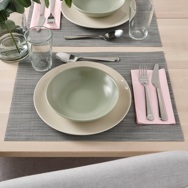 Tovagliette con posate, ciotole e bicchieri ordinatamente disposti per mangiare.