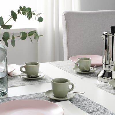Tavola alla moda con tazze verdi, piatti rosa e caffettiera argentata, pronta per la pausa tè o caffè. L'eucalipto aggiunge un tocco di freschezza.