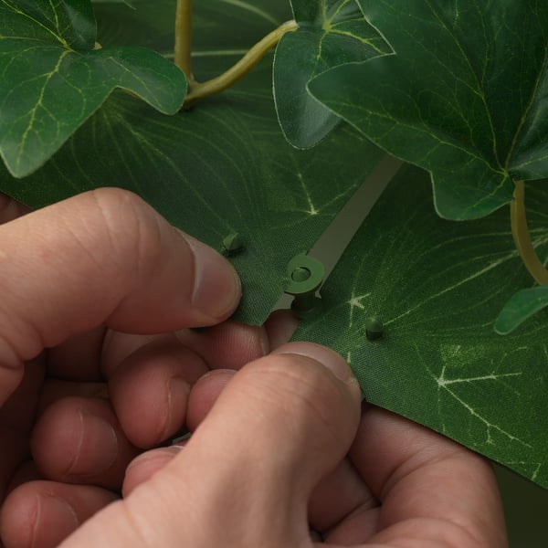 Le mani assemblano pannelli murali di piante verdi a incastro.