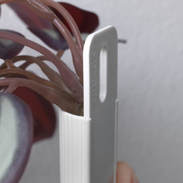 Una vista ravvicinata di una clip in metallo grigio etichettata applica che tiene saldamente uno stelo di pianta verde e realistico.