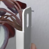 Una vista ravvicinata di una clip in metallo grigio etichettata applica che tiene saldamente uno stelo di pianta verde e realistico.