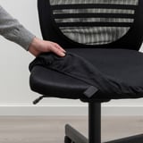 La mano regola il sedile ergonomico delle sedie da ufficio, mostrando un rivestimento rimovibile e lavabile per comfort e facilità di pulizia.