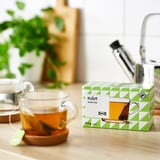 Scatola di bustine di tè verde sul tavolo vicino alla tazza da tè.