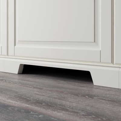Zoccolo nero con apertura per la ventilazione sotto l'armadio bianco.