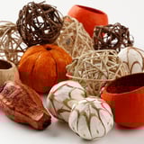 Collezione decorativa di zucche e sfere intrecciate. Articoli fatti a mano, naturali, nei colori arancione e crema. Ideale per l'arredamento autunnale.