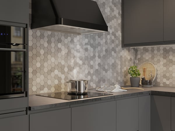 Cucina moderna con armadi neri, cappa, fornello, alzatina in piastrelle, luci, piante.