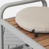 Cuscino da esterno su sedia a doghe con rivestimento idrorepellente.