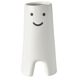 Vaso in ceramica bianca con disegno del volto sorridente, forma cilindrica con piccoli ritagli alla base.