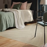 Camera da letto serena con tappeto, sedia, letto e arredamento beige FULLMAKT. Tappeto più grande della sedia, si adatta bene alla stanza.