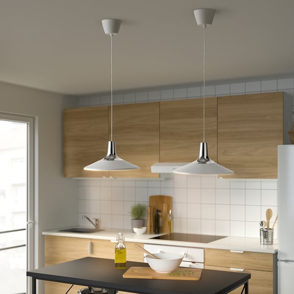 Cucina moderna con lampade a sospensione FYRTIOFYRA su tavolo scuro, dotata di ciotola, bottiglia e tagliere.