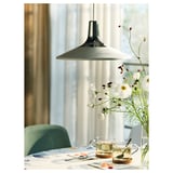 Moderna sala da pranzo con lampada a sospensione bianca, sedia verde e vaso di fiori bianchi sul tavolo.