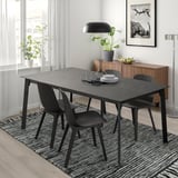 Tavolo da pranzo allungabile con struttura nera, piano in marmo, sedie, ampia finestra, lampada, credenza, pianta.