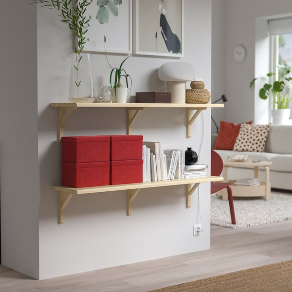 Soggiorno moderno con mensole in legno, scatole di velluto rosso, decorazioni e divano con cuscini.