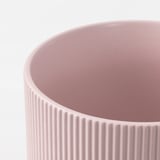 Primo piano di un vaso in gres rosa liscio con scanalature verticali, che ne mostra la trama fine e la lavorazione artigianale.