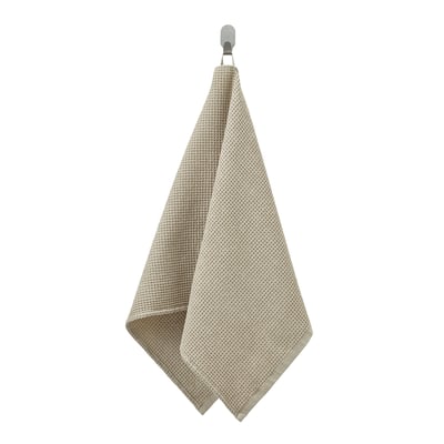 Un asciugamano beige e texturizzato chiamato GULLDYNA, realizzato in cotone riciclato. Ha un anello in cima per appenderla.
