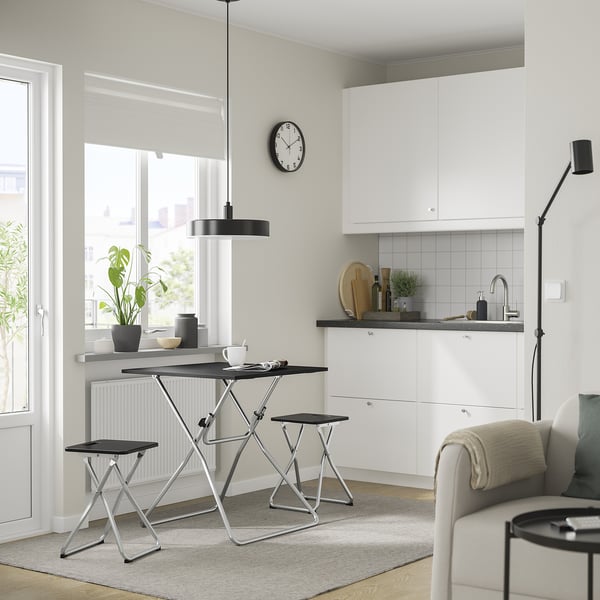 Cucina moderna con armadi bianchi, tavolo e sgabello in metallo nero, grande finestra, compatta per la conservazione, elegante lampada a sospensione.