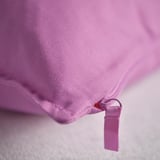 Primo piano della fodera del cuscino rosa morbida e solida con cerniera, che mostra consistenza e qualità.